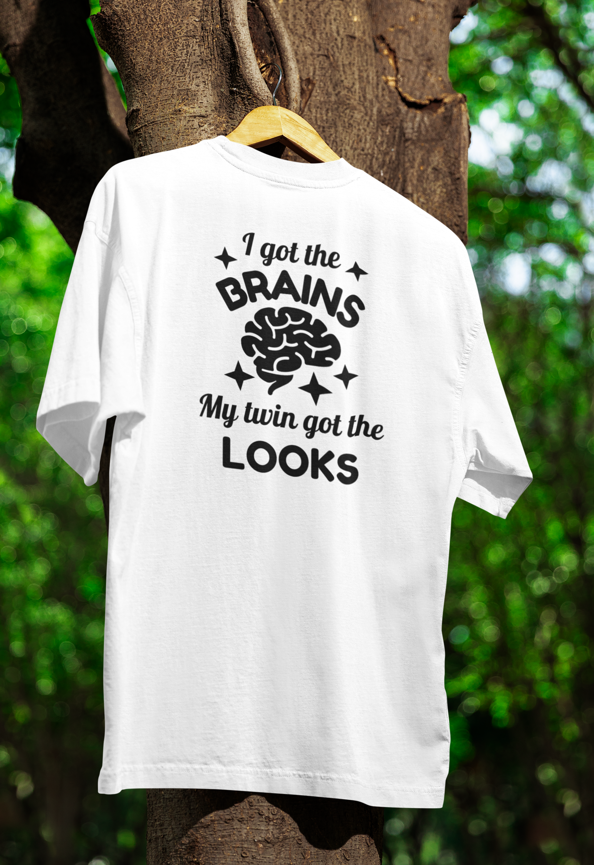 White t-shirt for twins with humorous text design on a hanger against a natural background