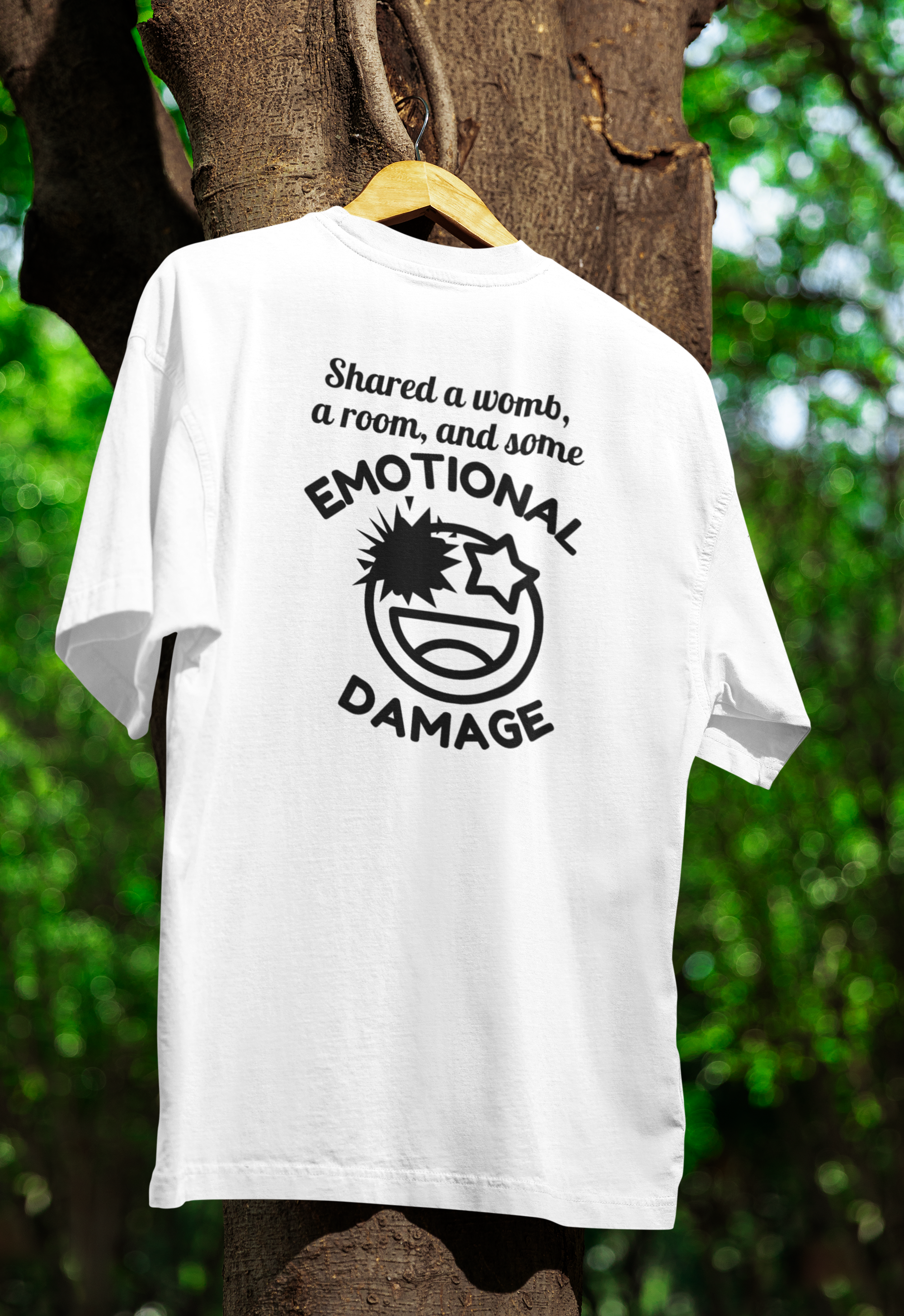 White t-shirt for twins with black text and graphic on a wooden hanger against a tree and green foliage background