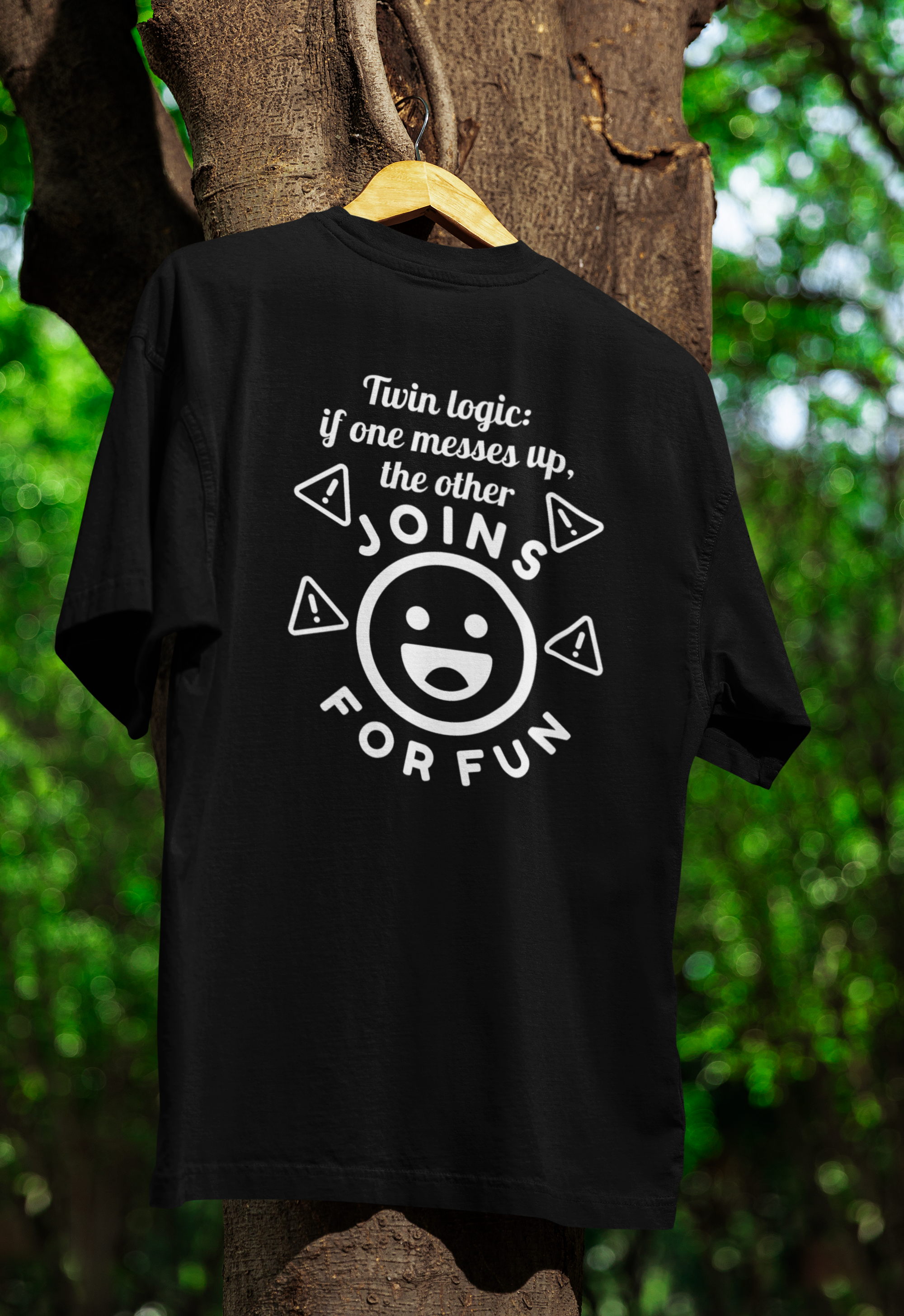Black t-shirt for twins with white text and graphics on a wooden hanger against a natural background