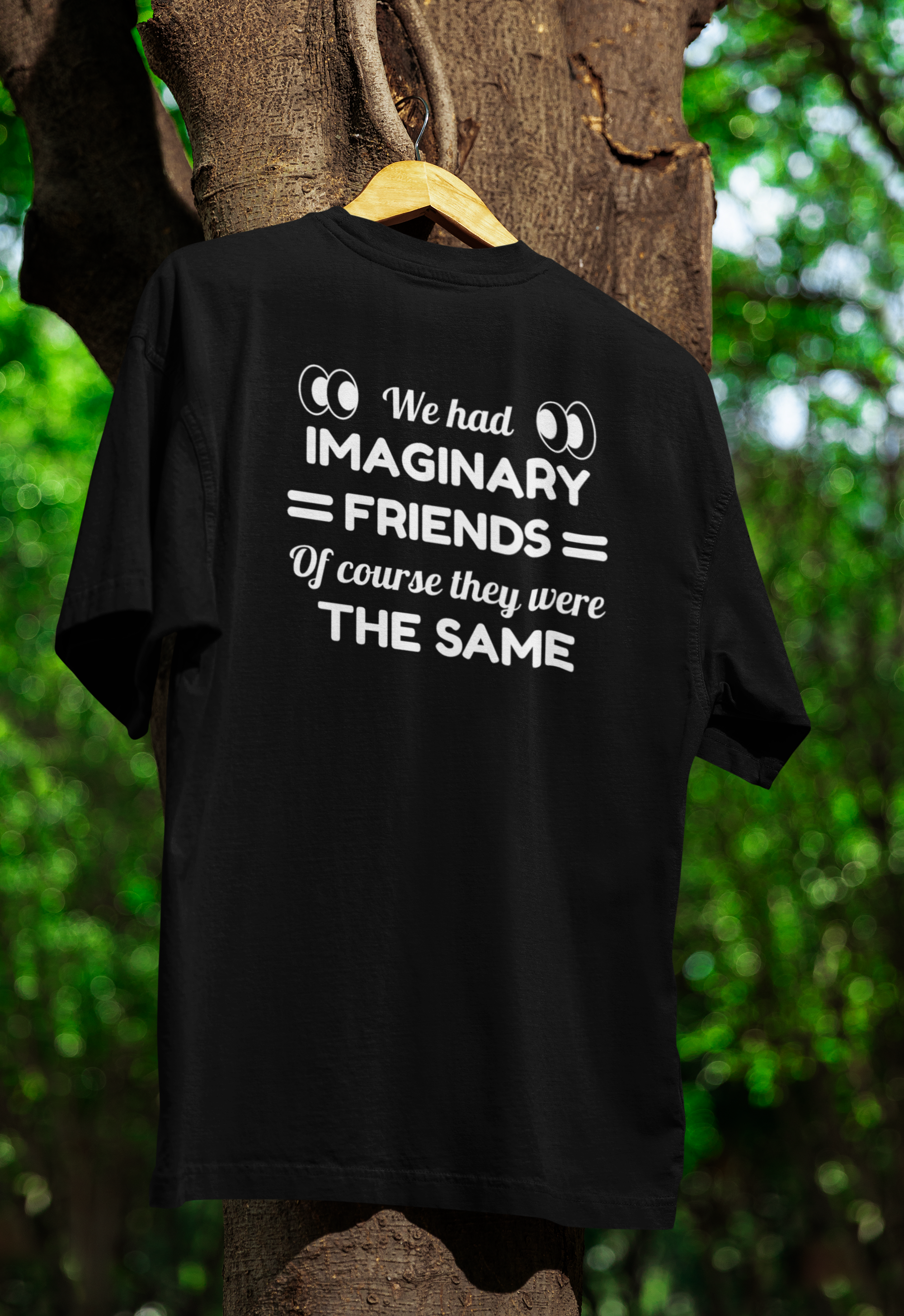 Black t-shirt for twins with humorous text design on a hanger against a natural background