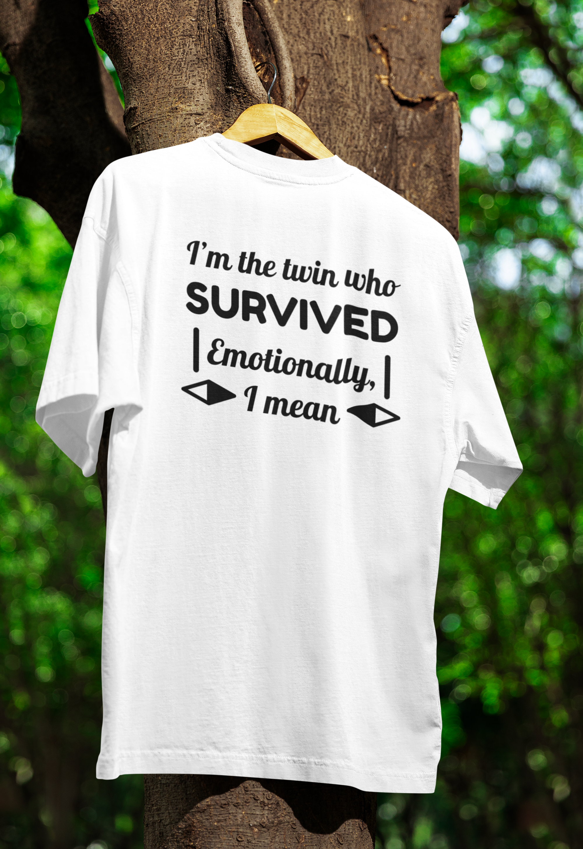 White t-shirt for twins with humorous text on a wooden hanger against a tree and green foliage background