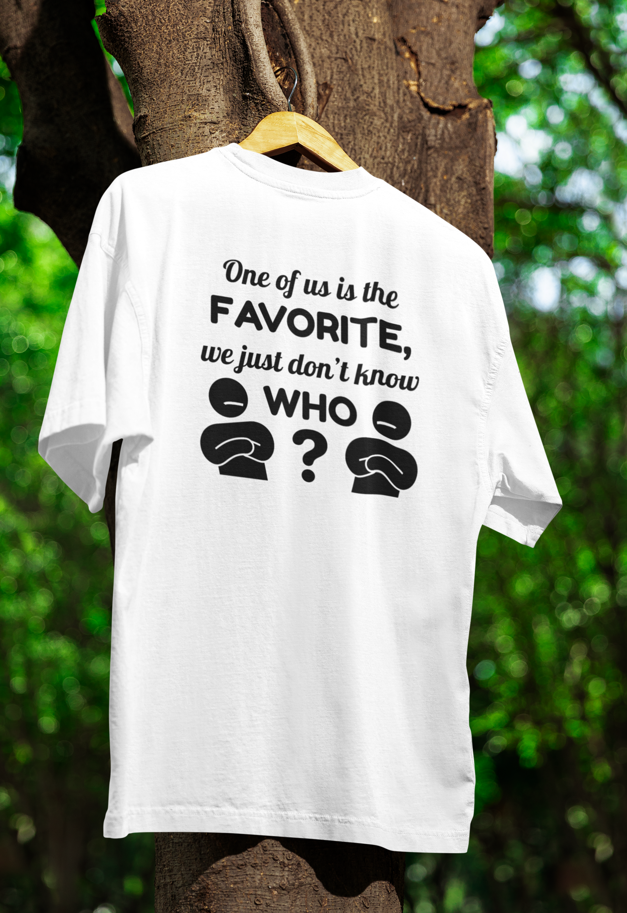 White t-shirt with black text and question marks on a wooden hanger against a tree background