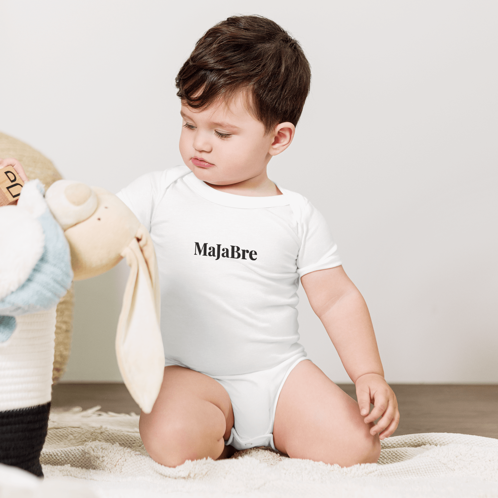 a baby wearing white twin bodysuit with black majabre sign 
