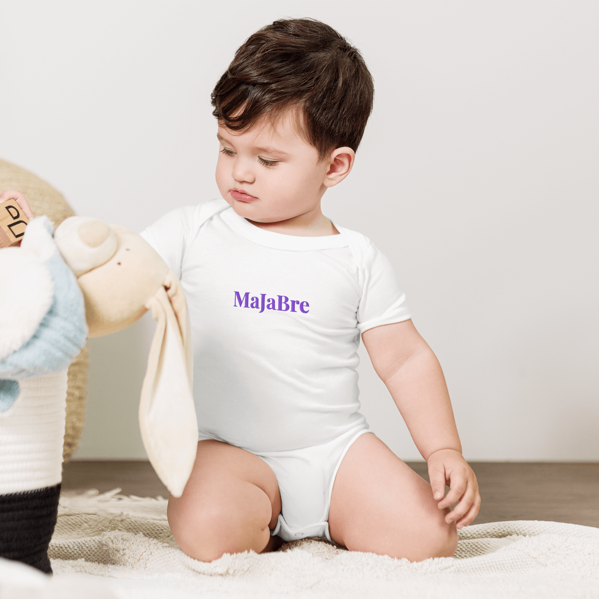 a baby wearing white twin bodysuit with purple majabre sign